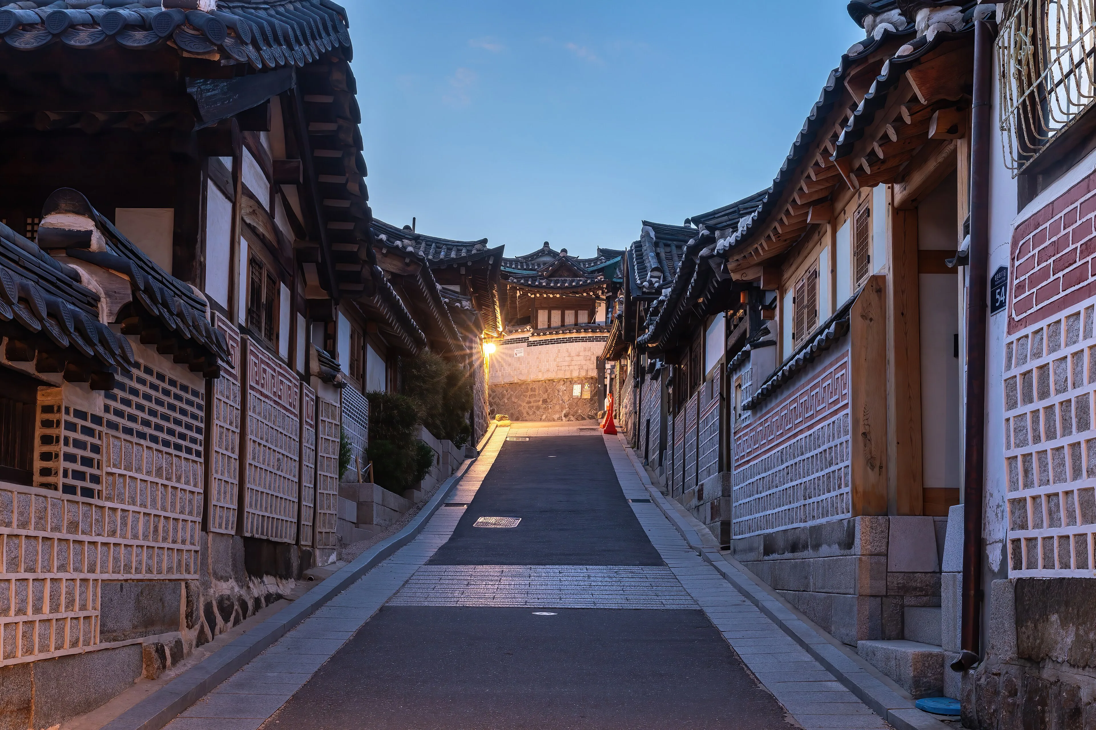 A lane of traditional hanok houses with tiled roofs in Bukchon Hanok Village, Seoul, at blue hour