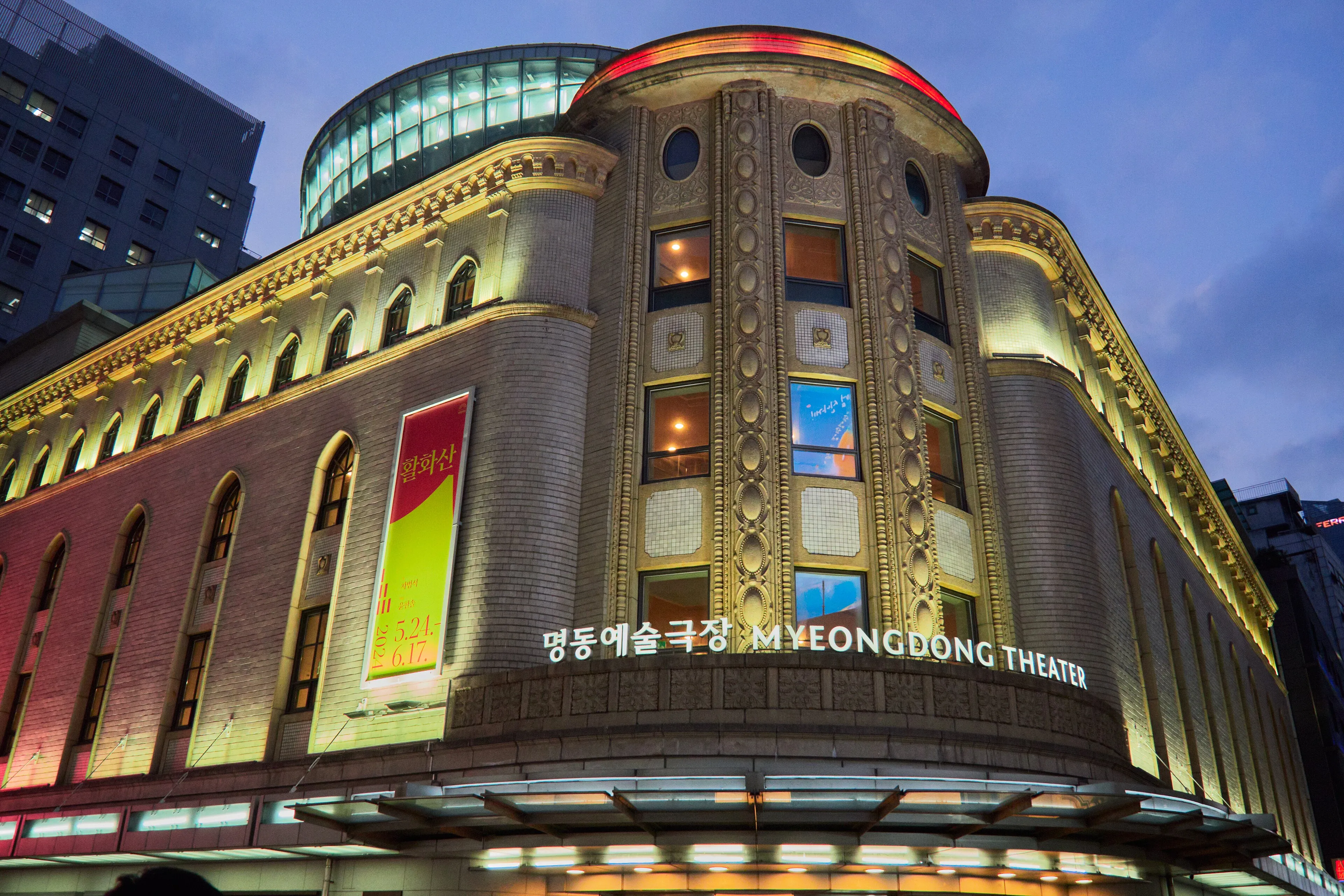 Shoppers under illuminated storefronts on a Myeongdong street in Seoul at night